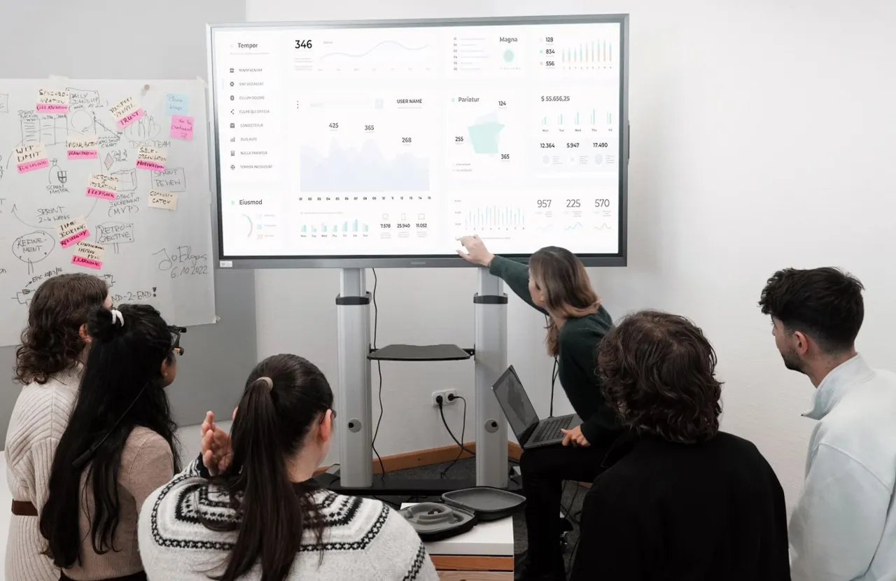 Marketing team reviewing an analytics dashboard on a large screen during a meeting